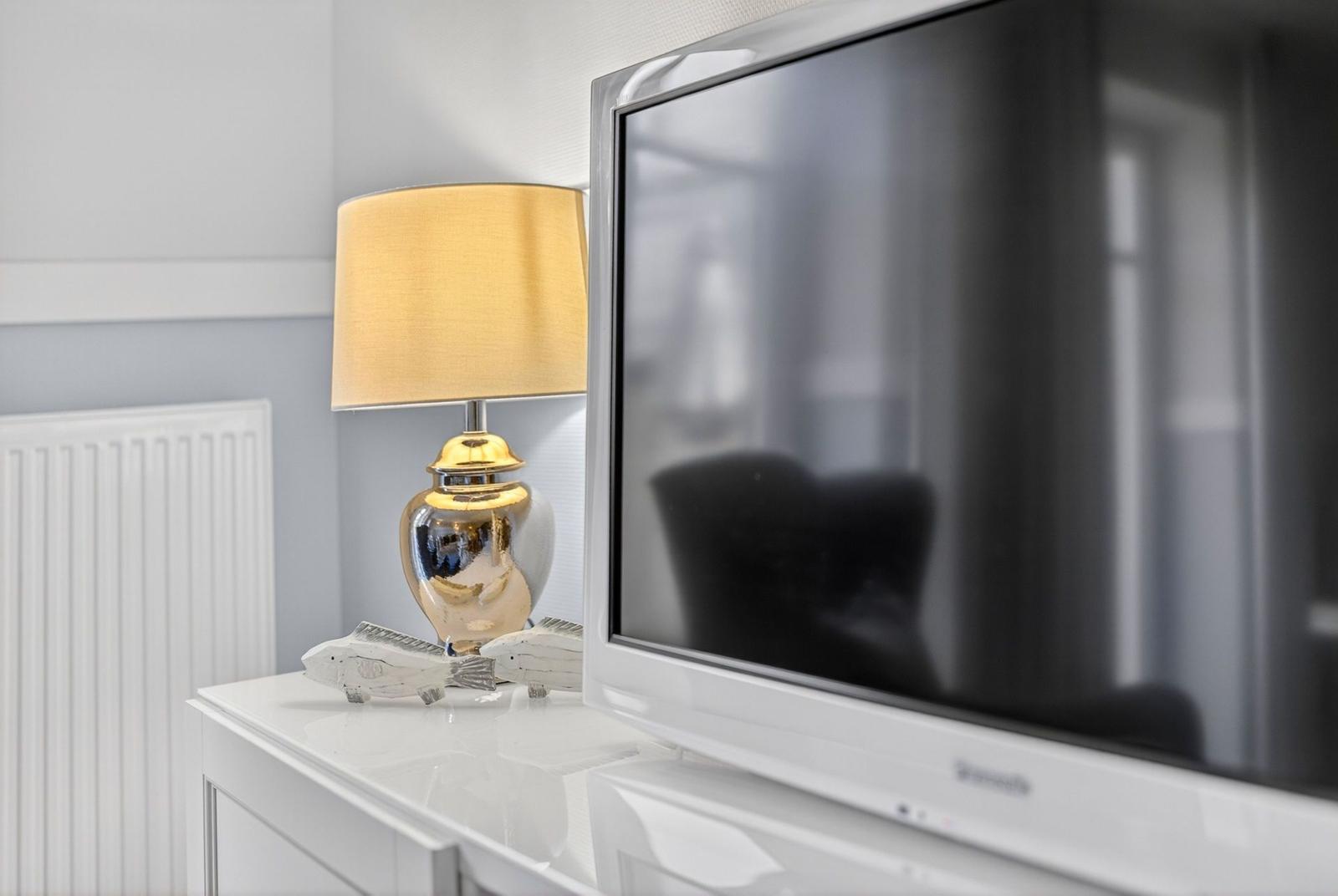TV auf weißem Möbelstück mit Lampe und Fischdekoration