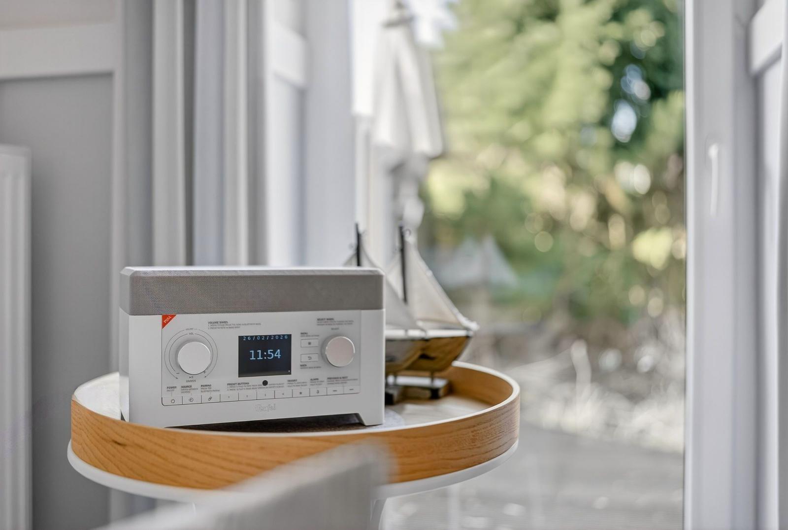 Radio auf Tisch neben Fenster mit Blick auf Garten