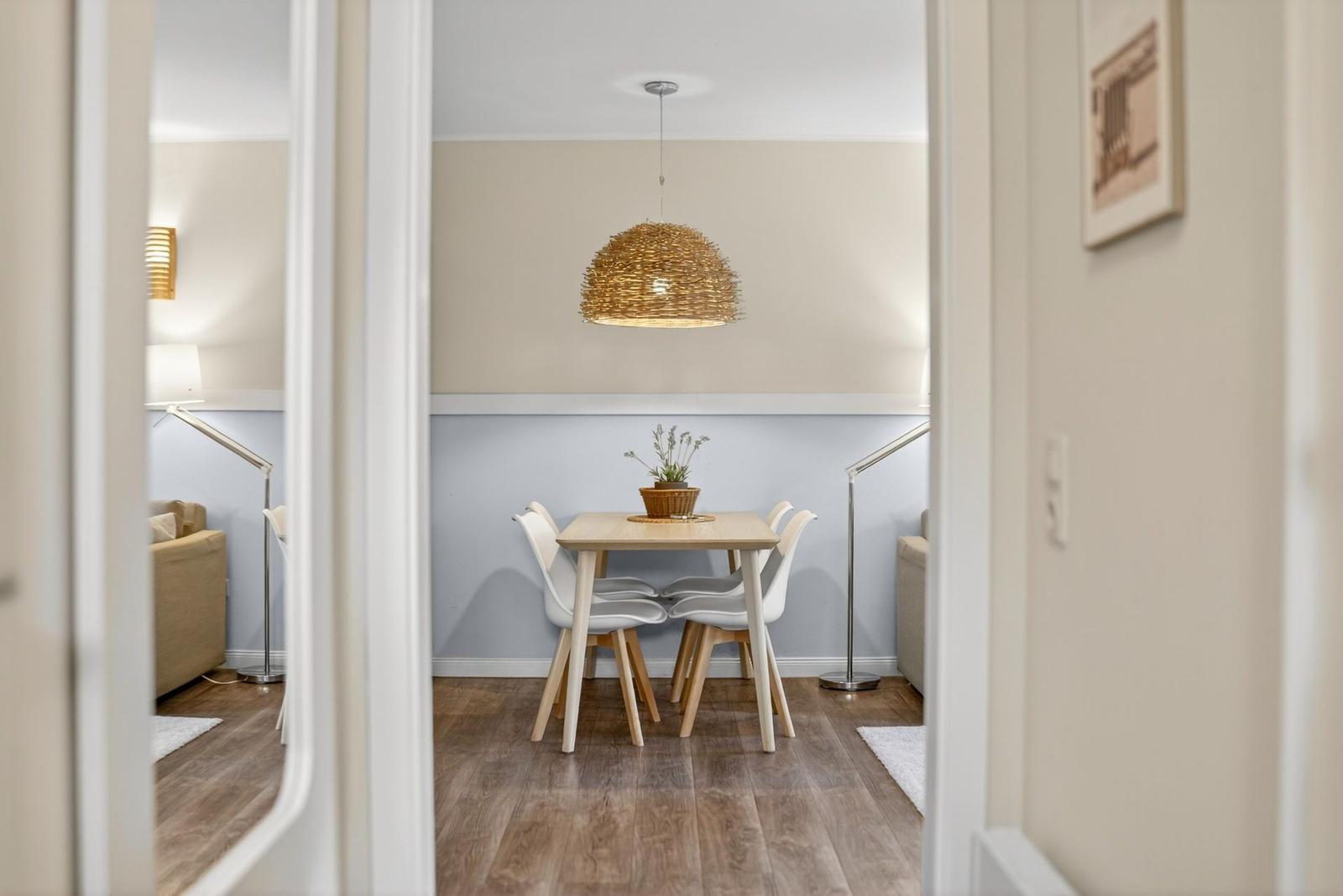 Esszimmer mit Tisch, vier Stühlen und einer hängenden Lampe.