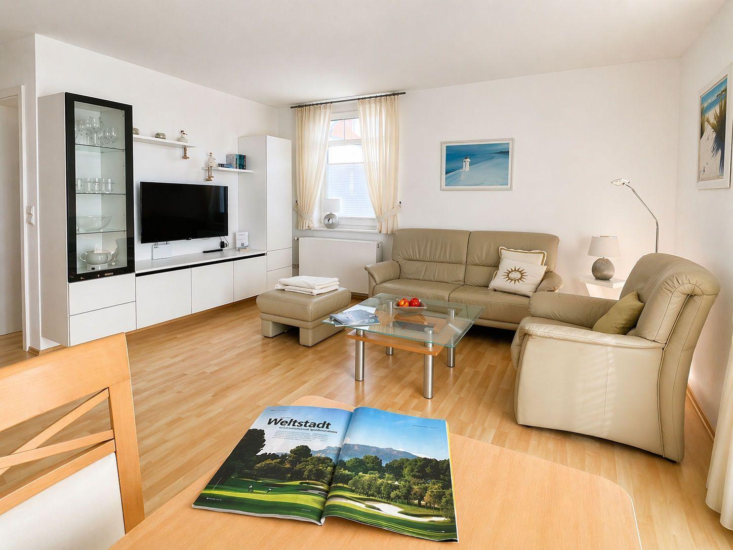 Living room with leather sofa, glass table, and TV mounted on wall.