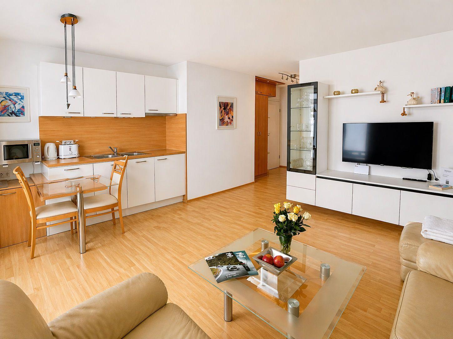 Living kitchen with dining area, glass table, sofa, and TV.