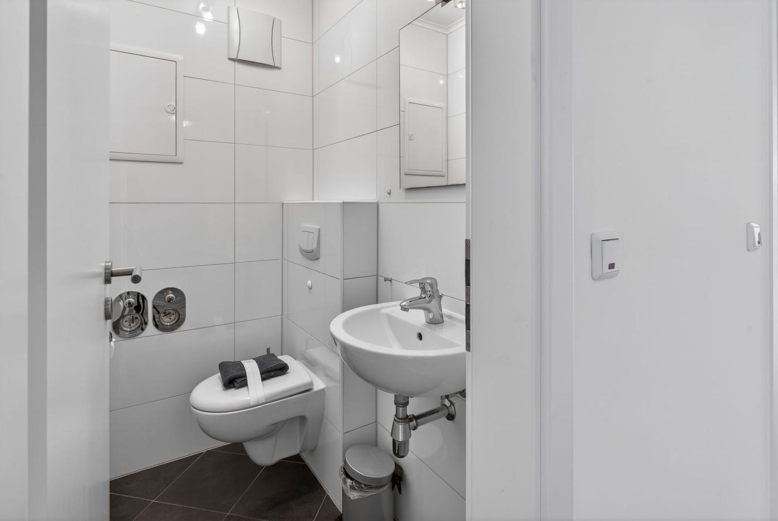 Badezimmer mit Toilette, Waschbecken und Spiegel.