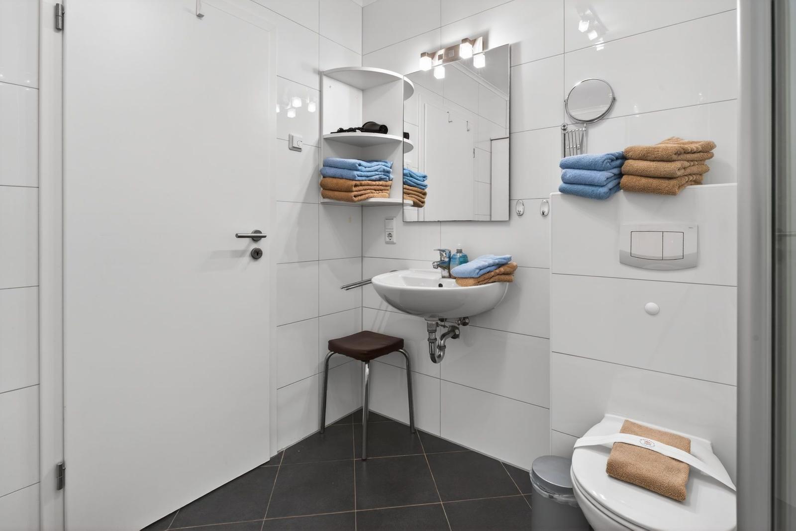 Badezimmer mit Waschbecken, Spiegel, Toilette und Handtüchern.