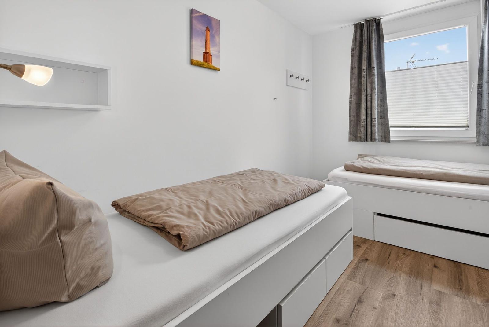 Schlafzimmer mit zwei Matratzen und Holzboden. An der Wand hängt ein Bild.
