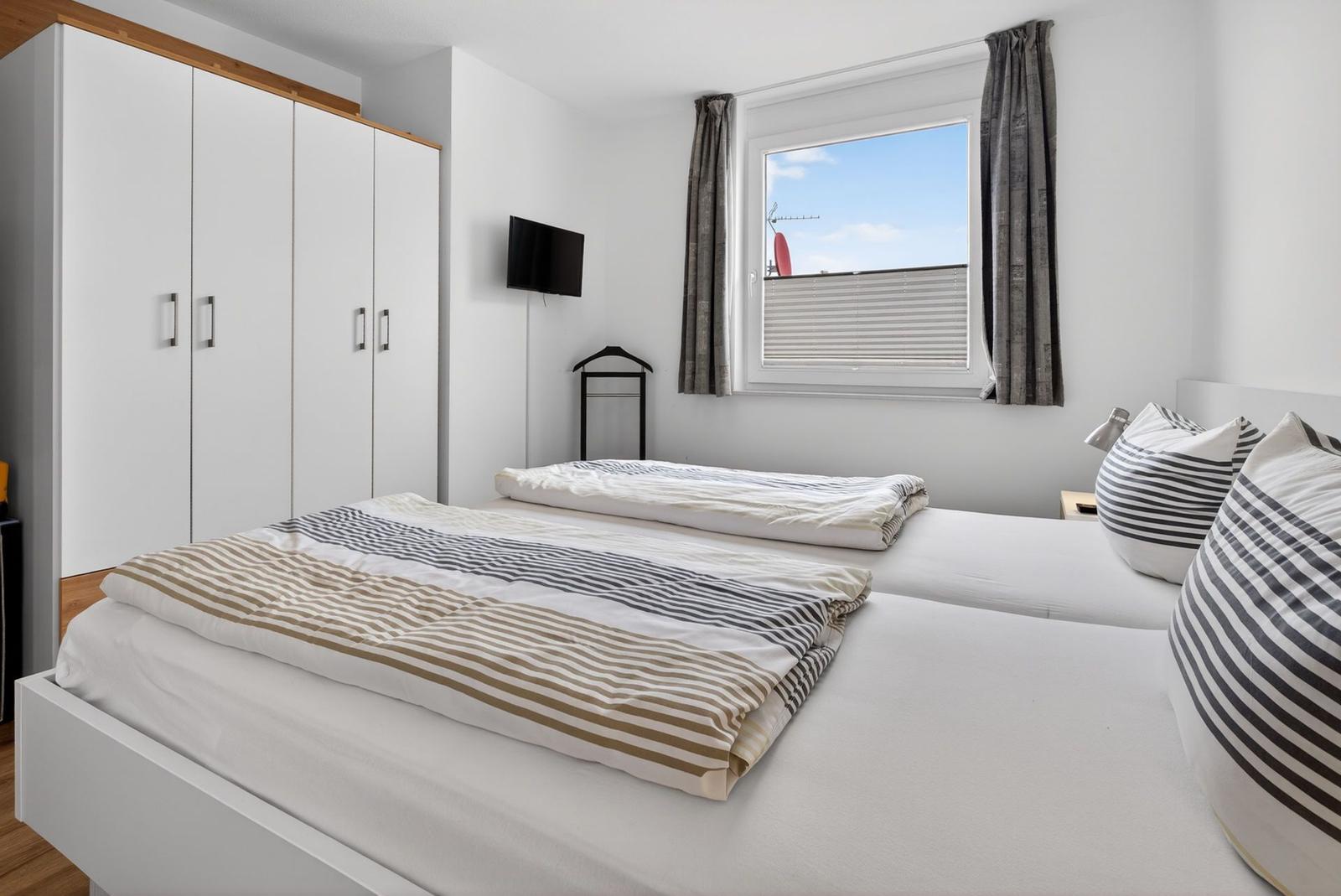 Schlafzimmer mit Doppelbett, Kleiderschrank und Fenster mit Blick.