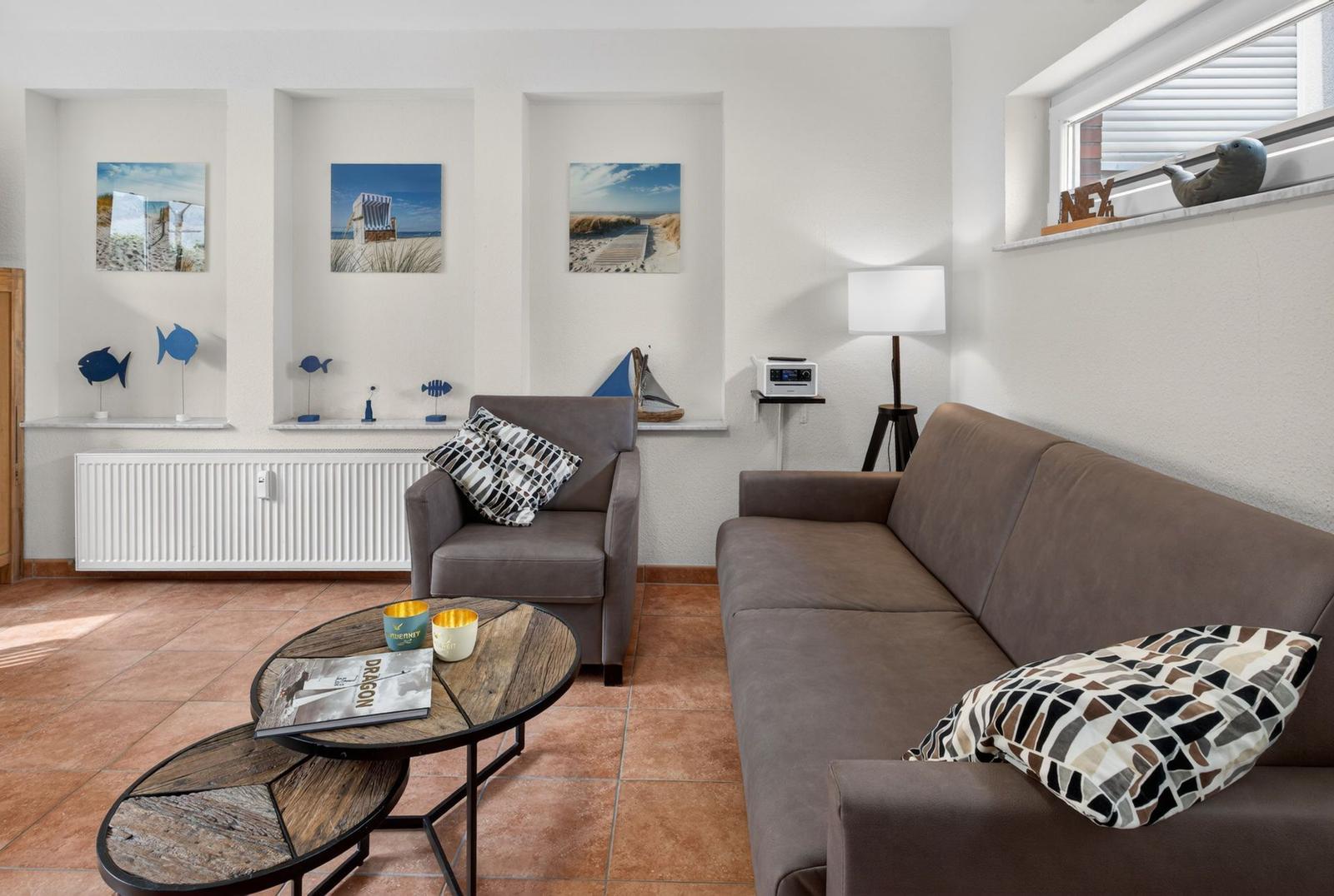 Wohnzimmer mit Sofa, Sessel, Tisch und Wandbildern