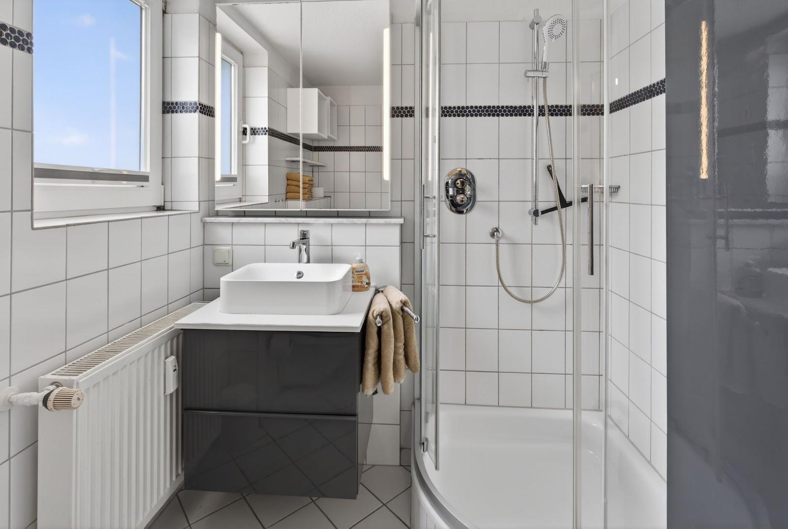Badezimmer mit Dusche, Waschbecken und Fenster