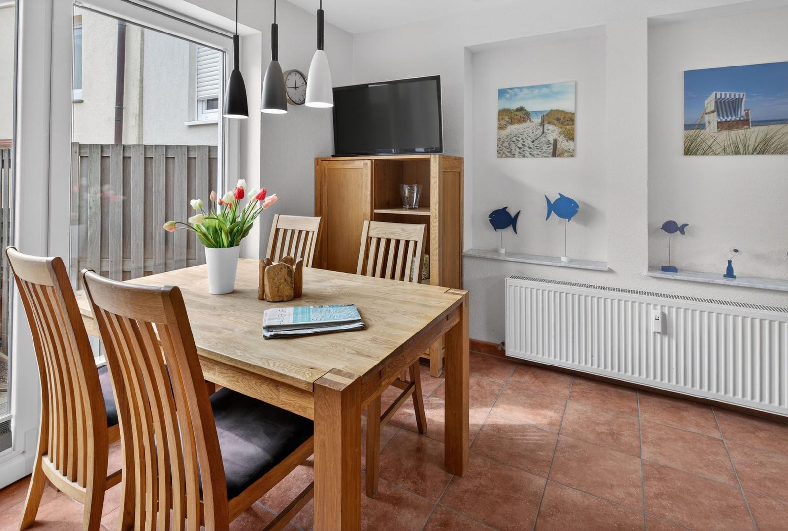 Esszimmer mit Holztisch, Stühlen und Fernseher. Wandbilder und Fischdekoration.