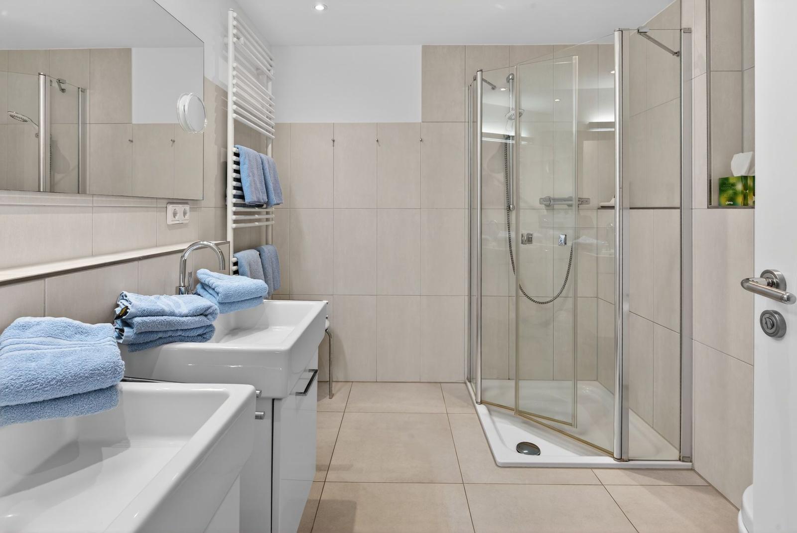 Badezimmer mit Dusche, Waschbecken und Handtüchern.