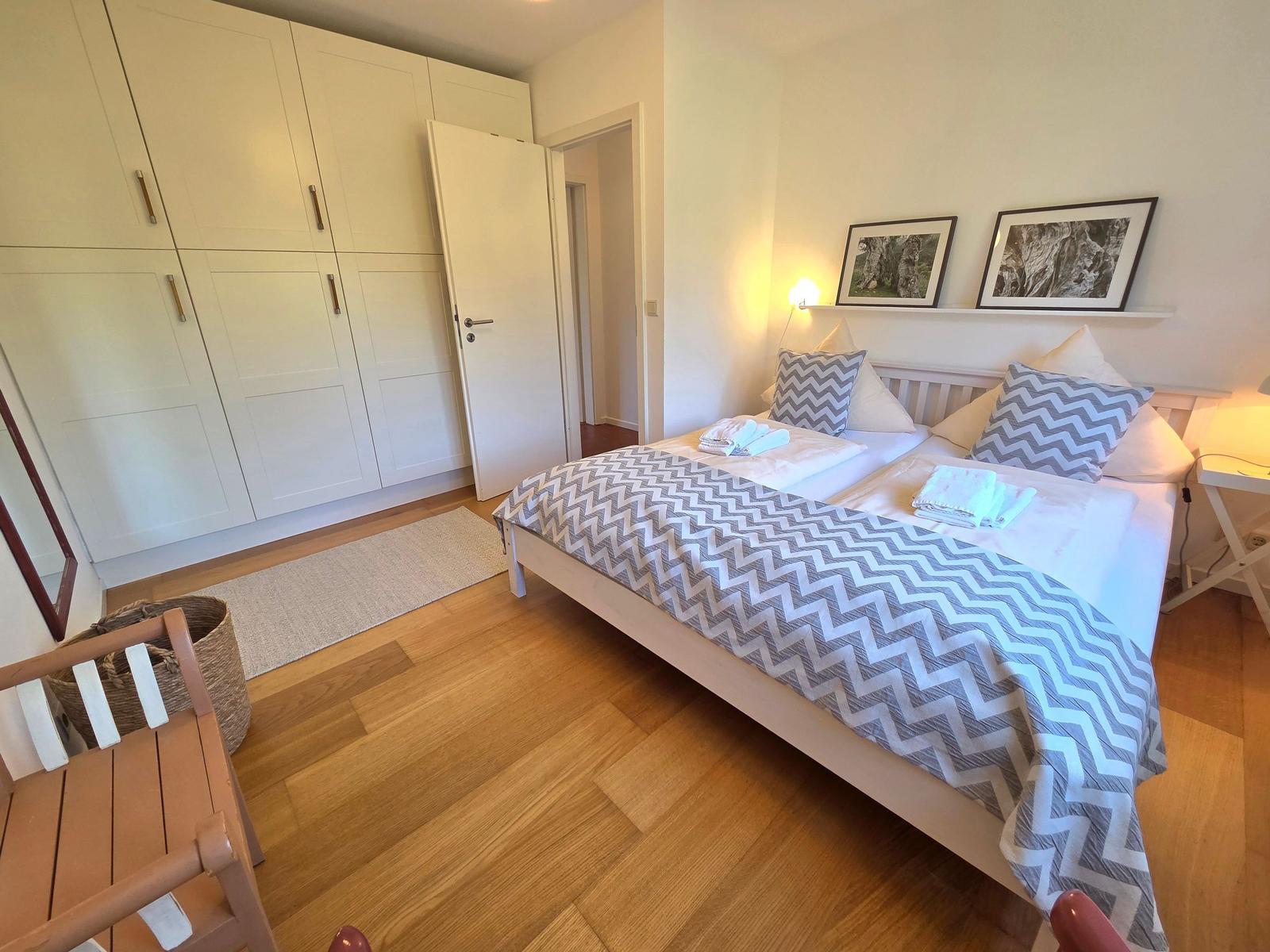 Schlafzimmer mit Doppelbett, Kleiderschrank und Holzboden.