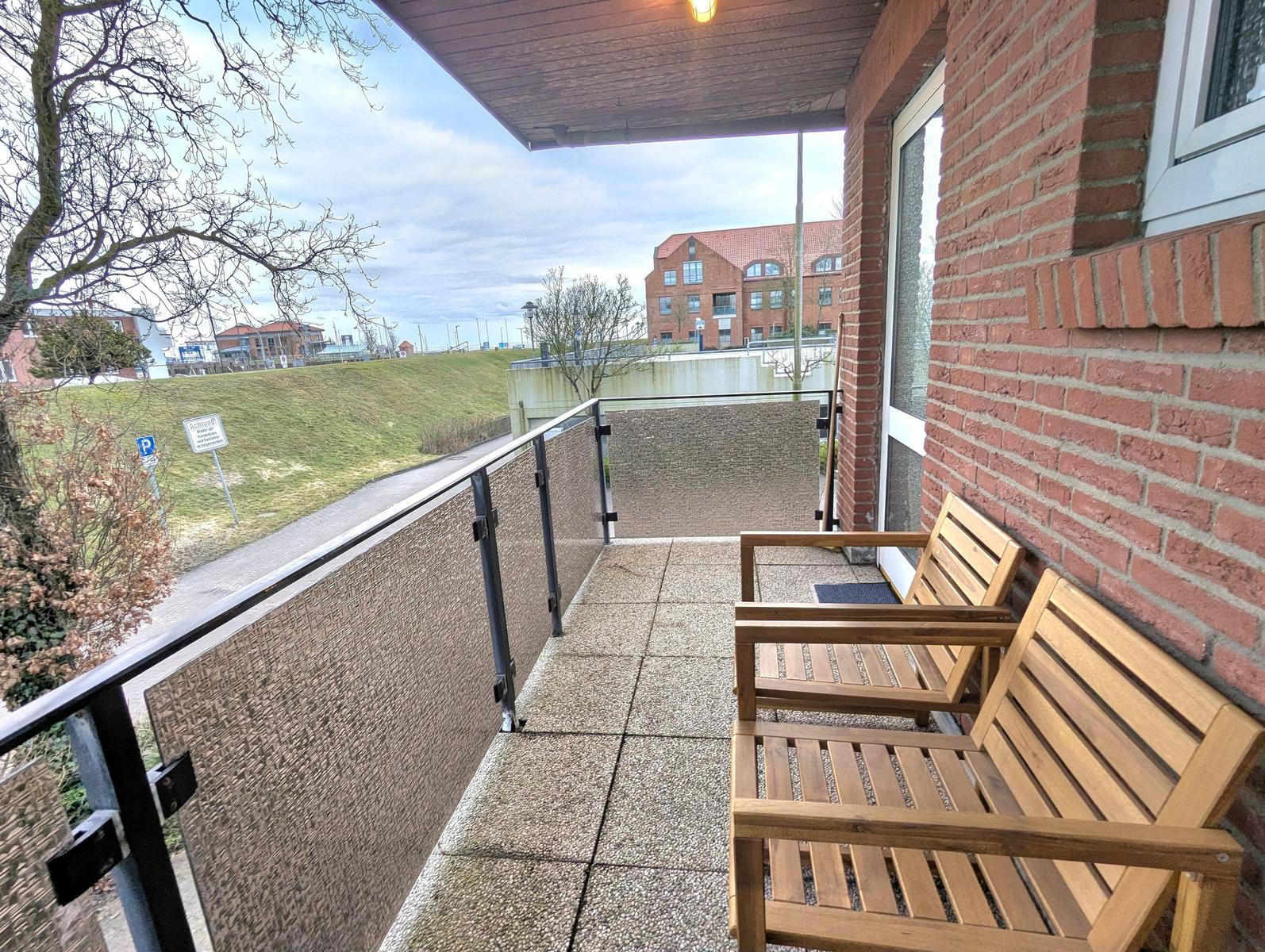 Terrasse mit zwei Holzstühlen und Blick auf Grünfläche und Gebäude