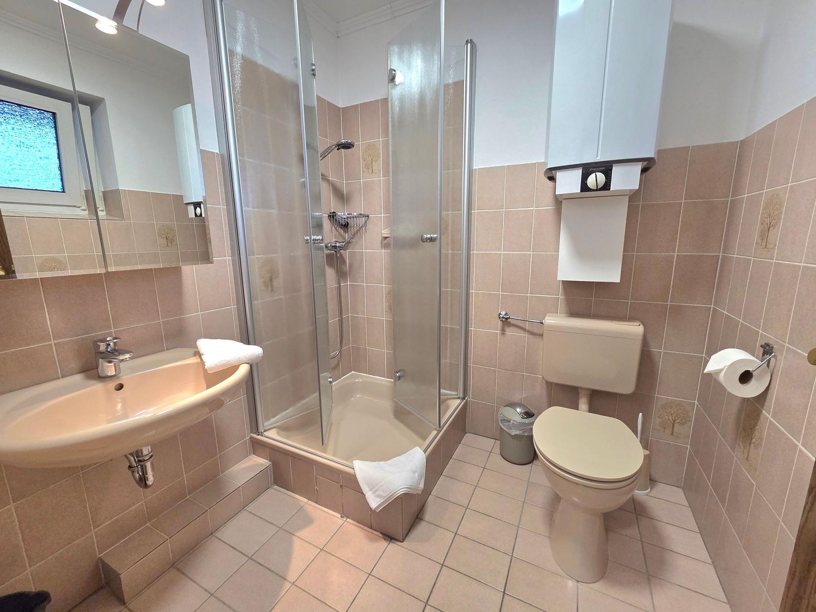 Badezimmer mit Dusche, Toilette und Waschbecken.