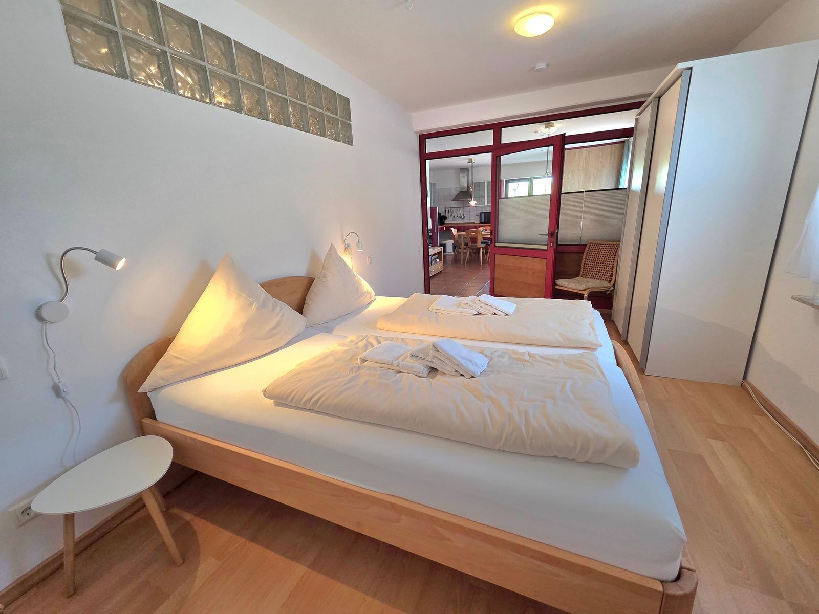 Bedroom with double bed, nightstand, and view into the kitchen.