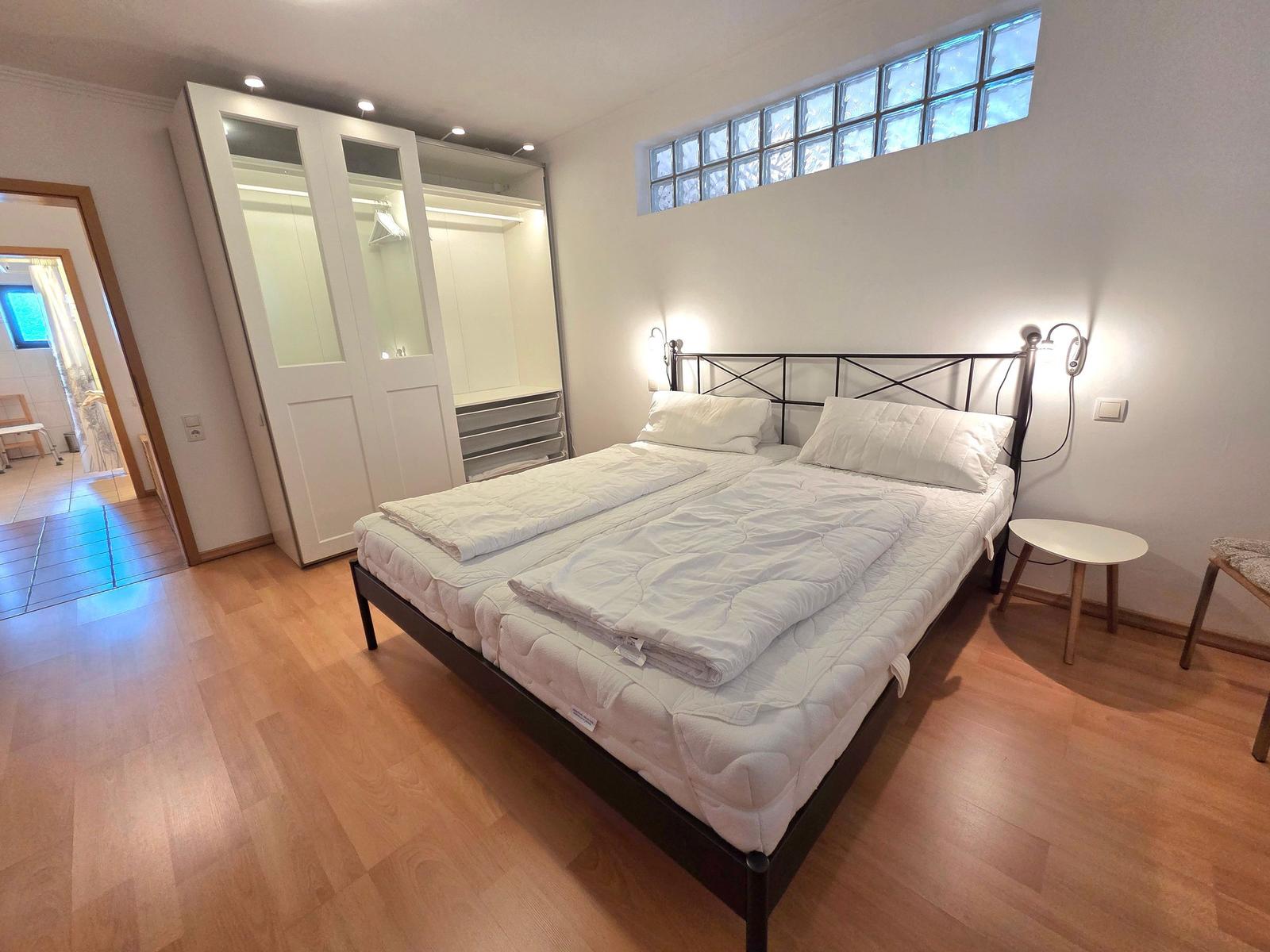 Bedroom with double bed, wardrobe, and hardwood floor.