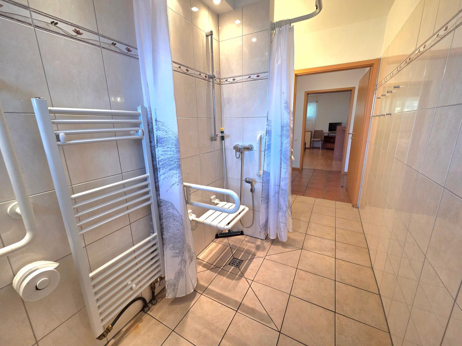 Shower with seat, shower curtain, and heater on wall
