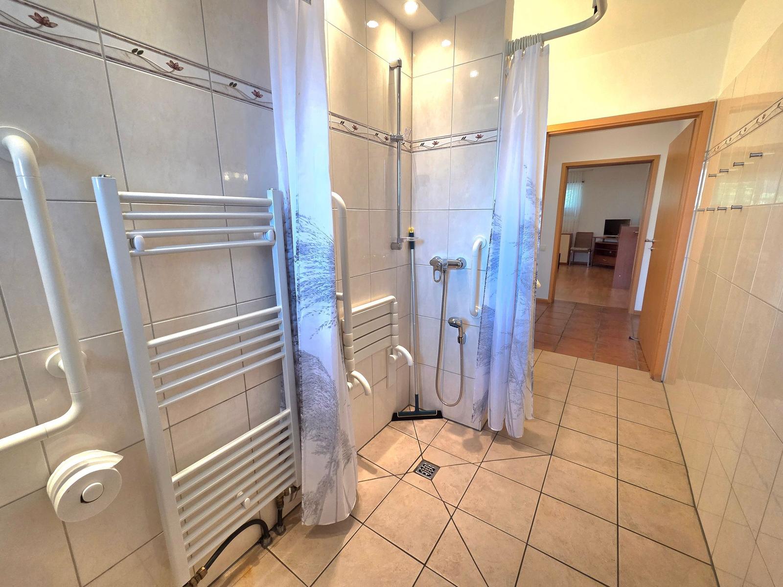 Shower with curtain and grab bar, heater and floor drain