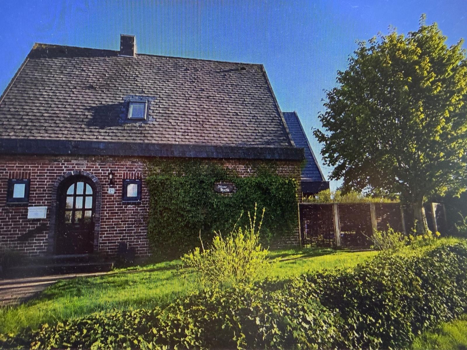 Haus mit Ziegelfassade, Dachfenster und grüner Umgebung