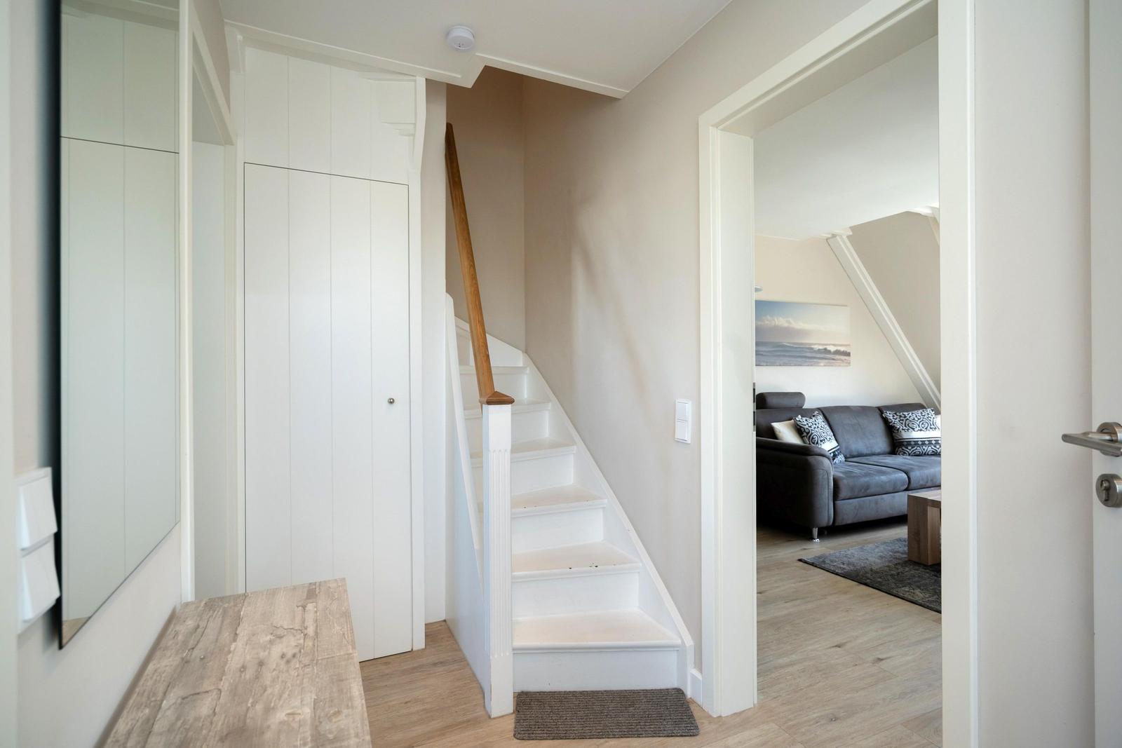Haus mit Treppe zur Wohnung, Wohnzimmer mit Sofa und Wandbild
