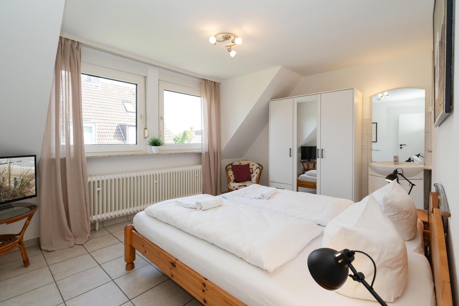 Schlafzimmer mit Doppelbett, Fenster, Schrank und Waschbecken