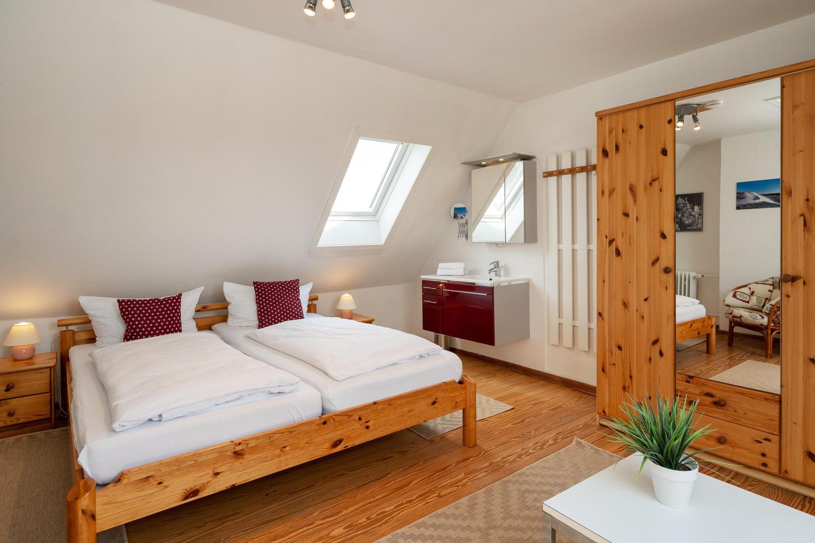 Zimmer mit Doppelbett, Dachschräge, Fenster und Badmöbel