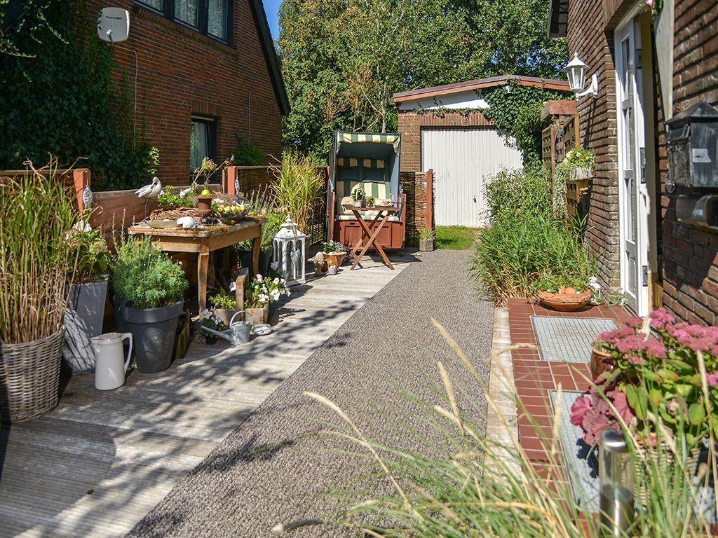 Backyard with terrace, plants, and garden furniture. Entrance door and mailbox on the wall.