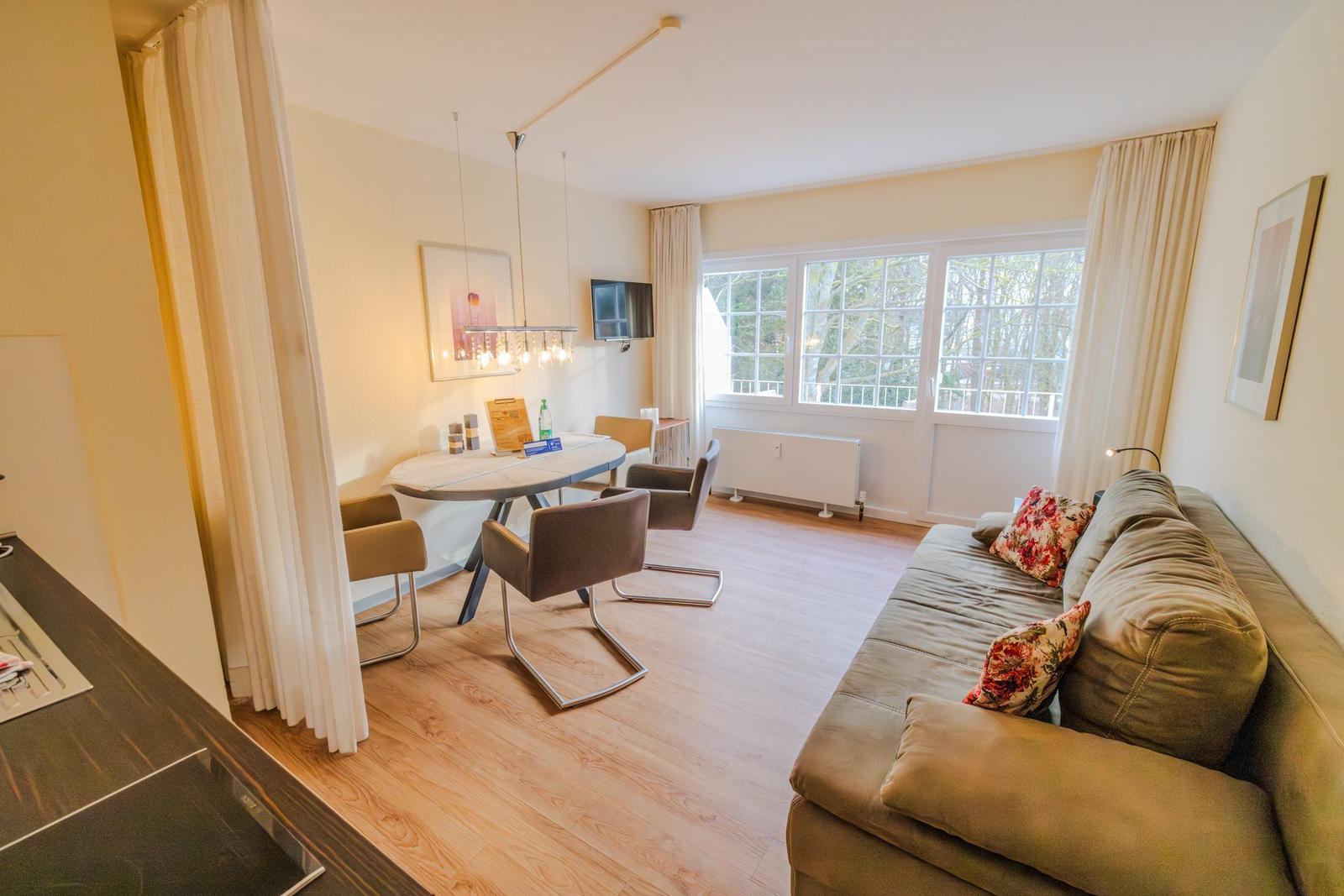 Wohn- und Essbereich mit Sofa, Tisch und Fenster zur Außenseite.