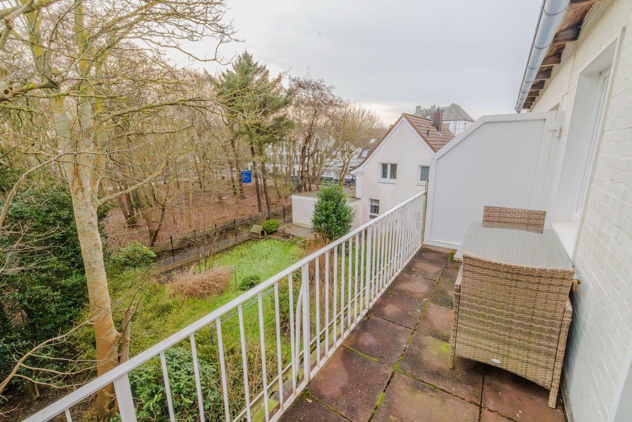 Terrasse mit Tisch und Stühlen, Blick auf grünen Garten und Nachbarhäuser.