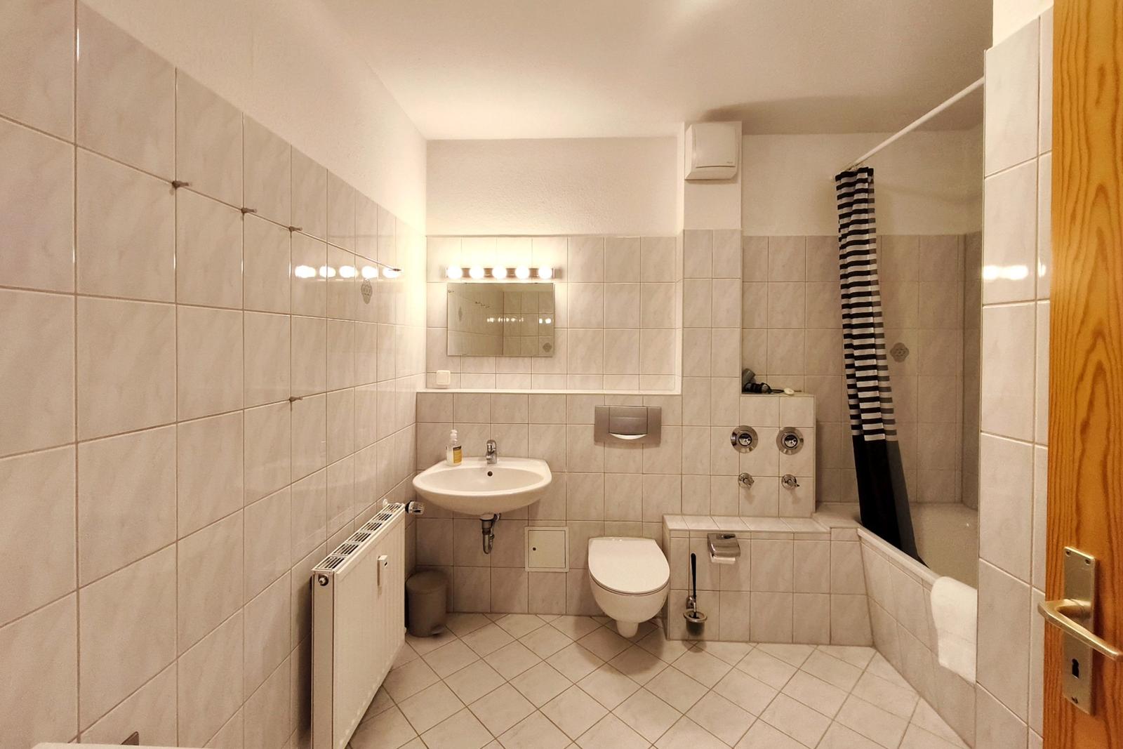 Modernes Badezimmer mit Badewanne und hellem Fliesenspiegel in Koserow