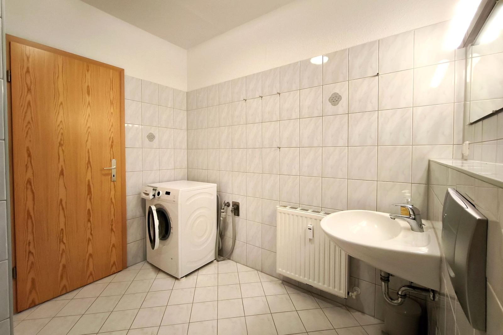 Sauberes Badezimmer mit Waschbecken und integrierter Waschmaschine