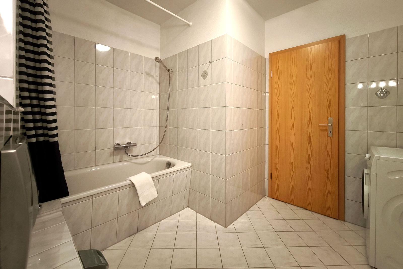 Weiß gefliestes Bad mit Badewanne für entspannte Urlaubsstunden