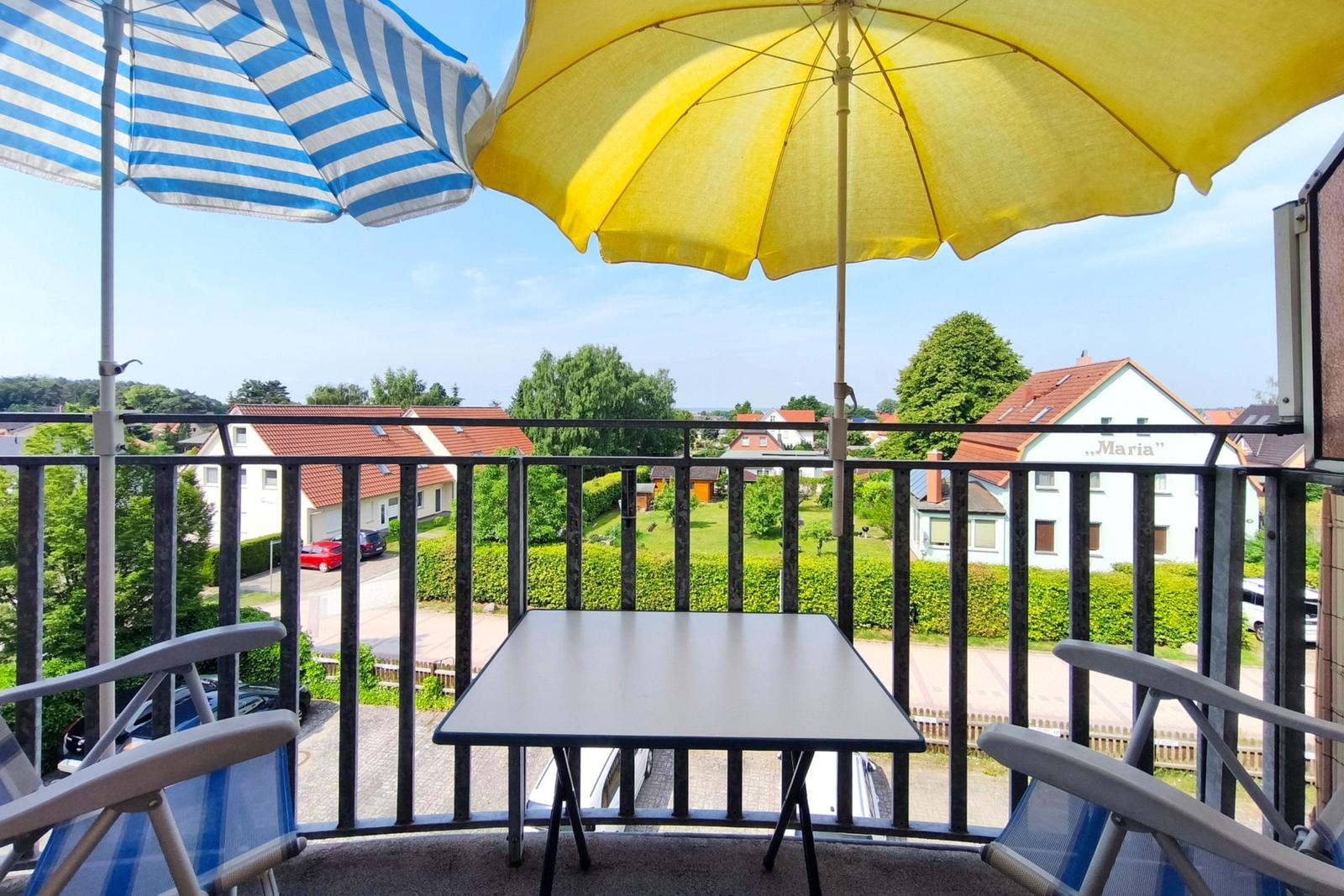 Sonniger Balkon mit Sitzmöbeln und gelbem Sonnenschirm im Sommer