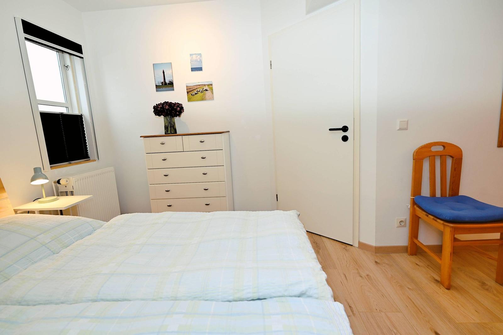 Schlafzimmer mit Bett, Schrank, Stuhl und Fenster.