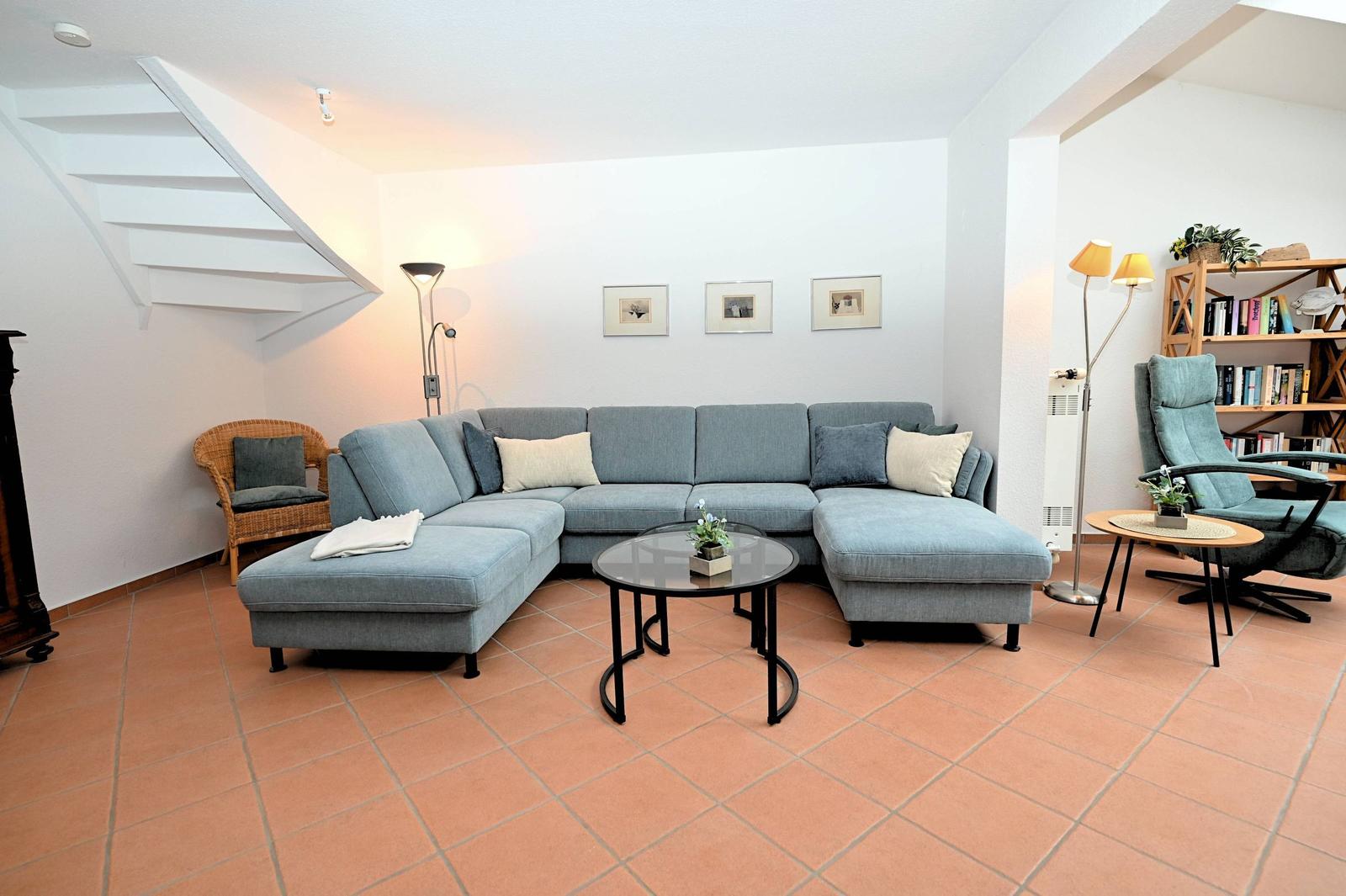 Ein Wohnzimmer mit einem grauen Sofa, einem runden Tisch und einem Bücherregal.