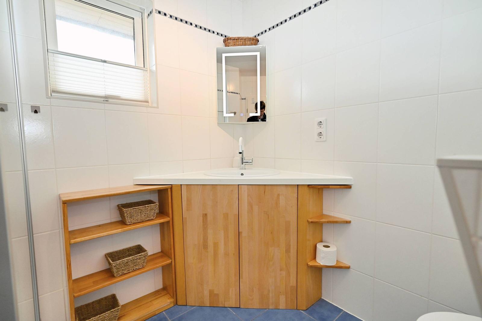 Badezimmer mit Waschbecken, Spiegel und Holzregalen.