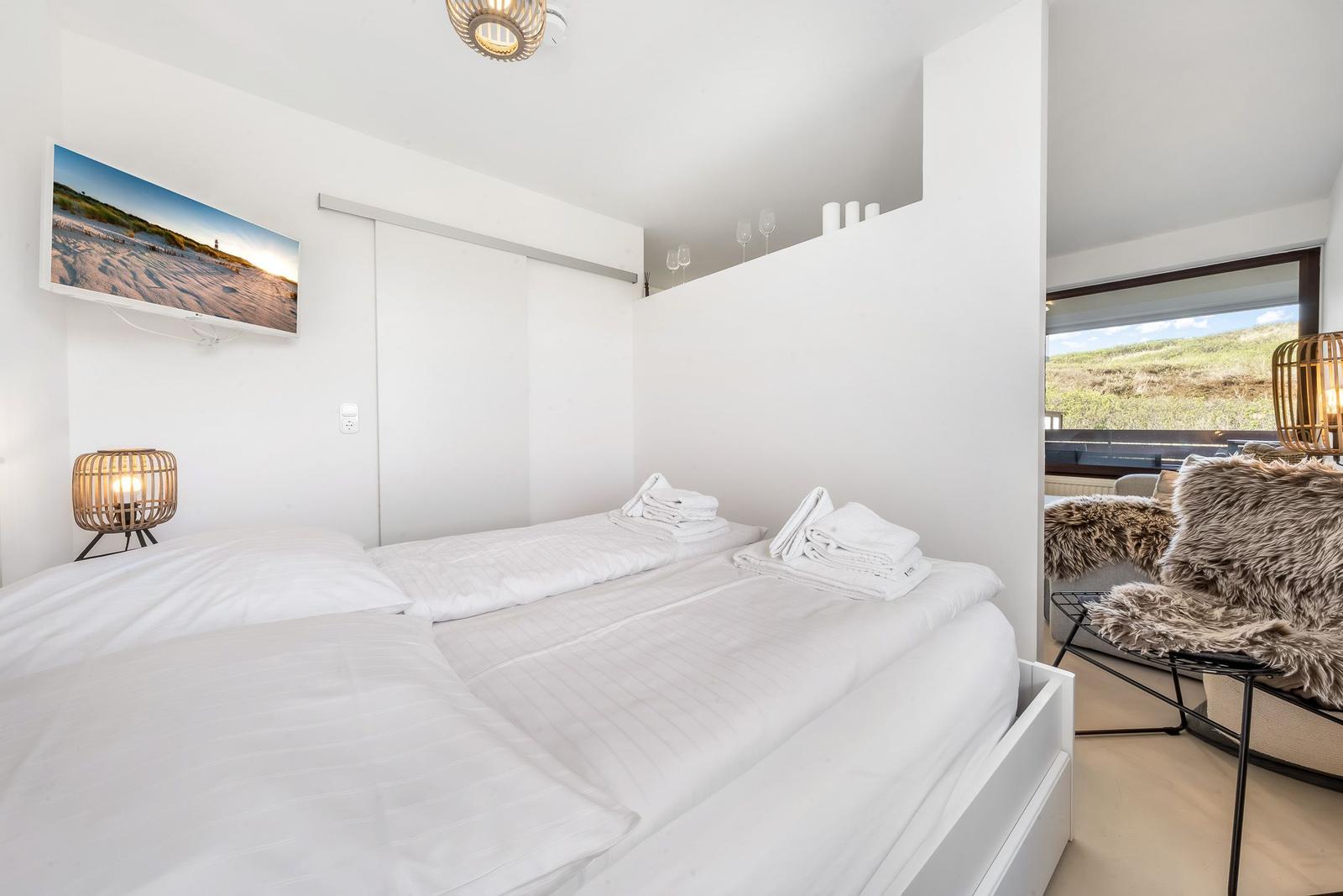 Bedroom with double bed, TV, and view of green field.