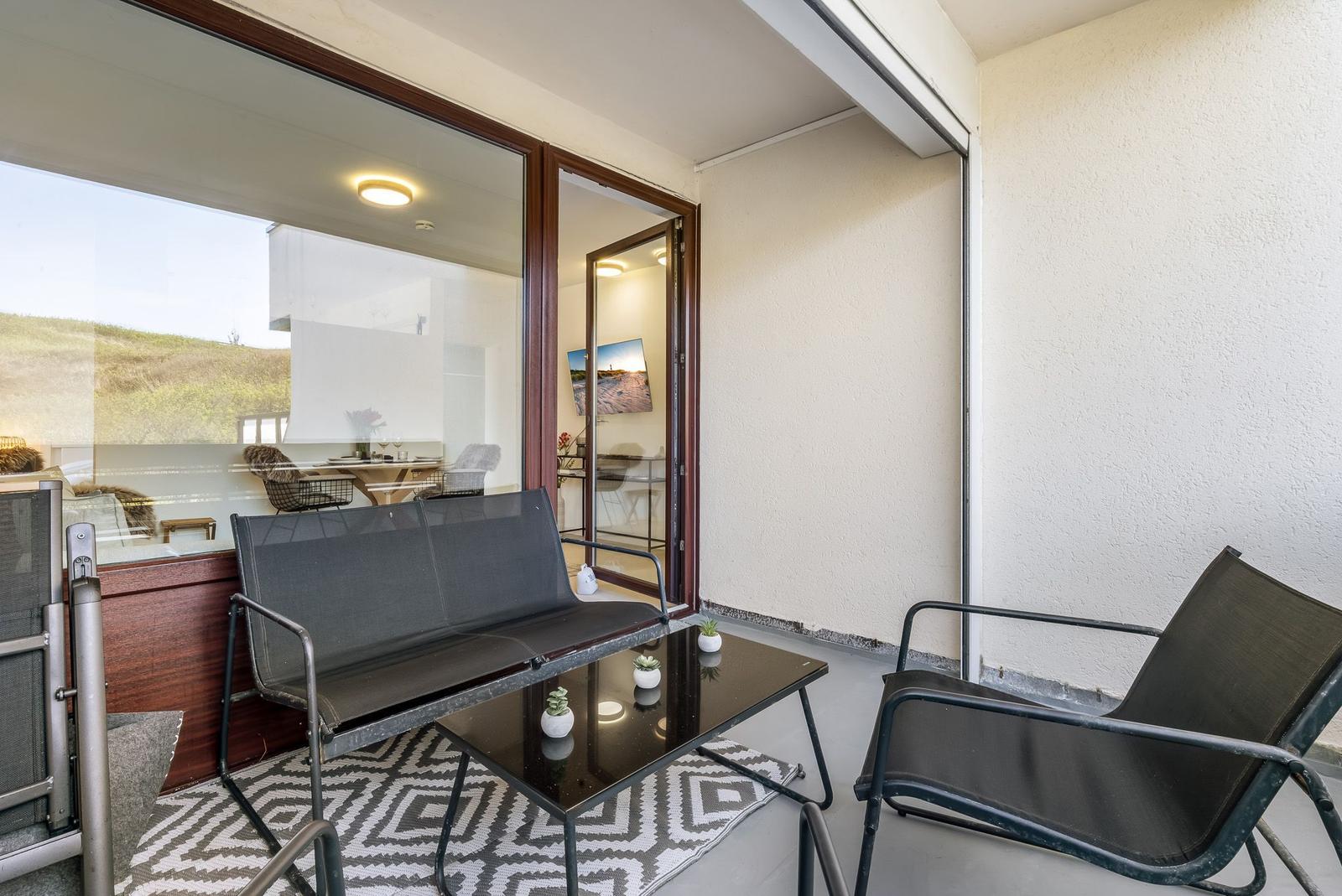 Terrace with seating and view into the house. Glass door and rug visible.