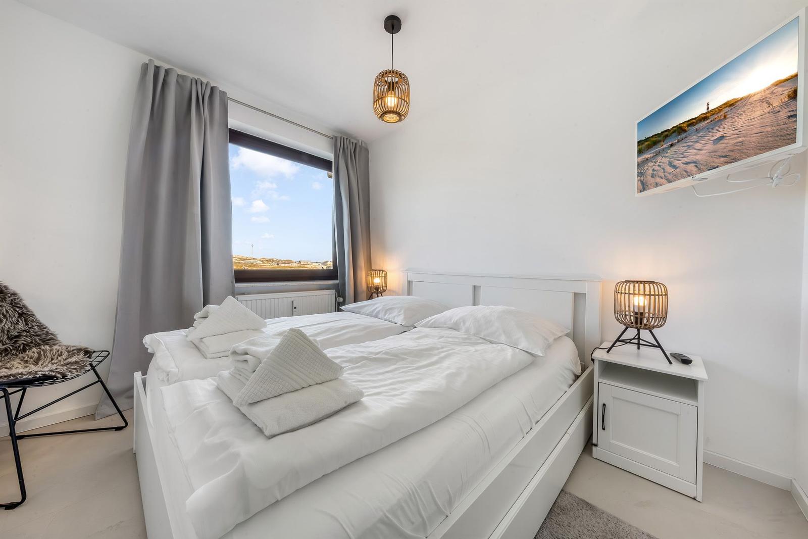 Bedroom with double bed, window, and wall picture.