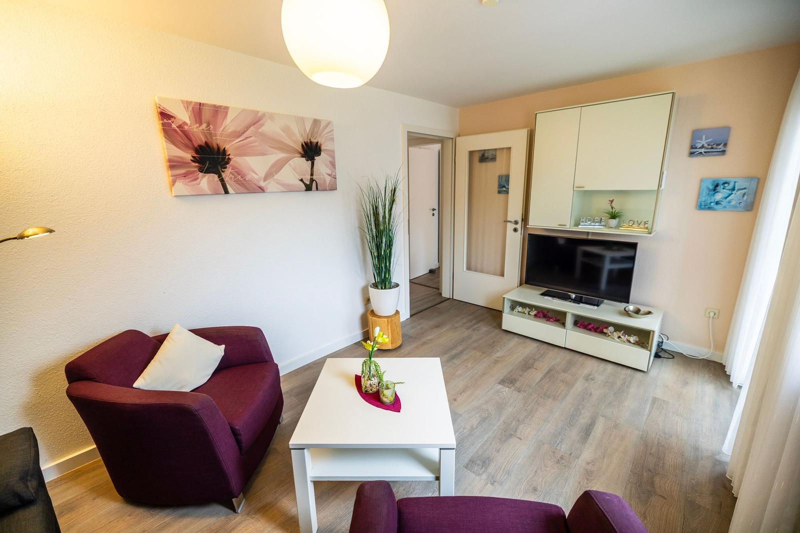 Wohnzimmer mit Sofa, Fernseher und Holzboden.