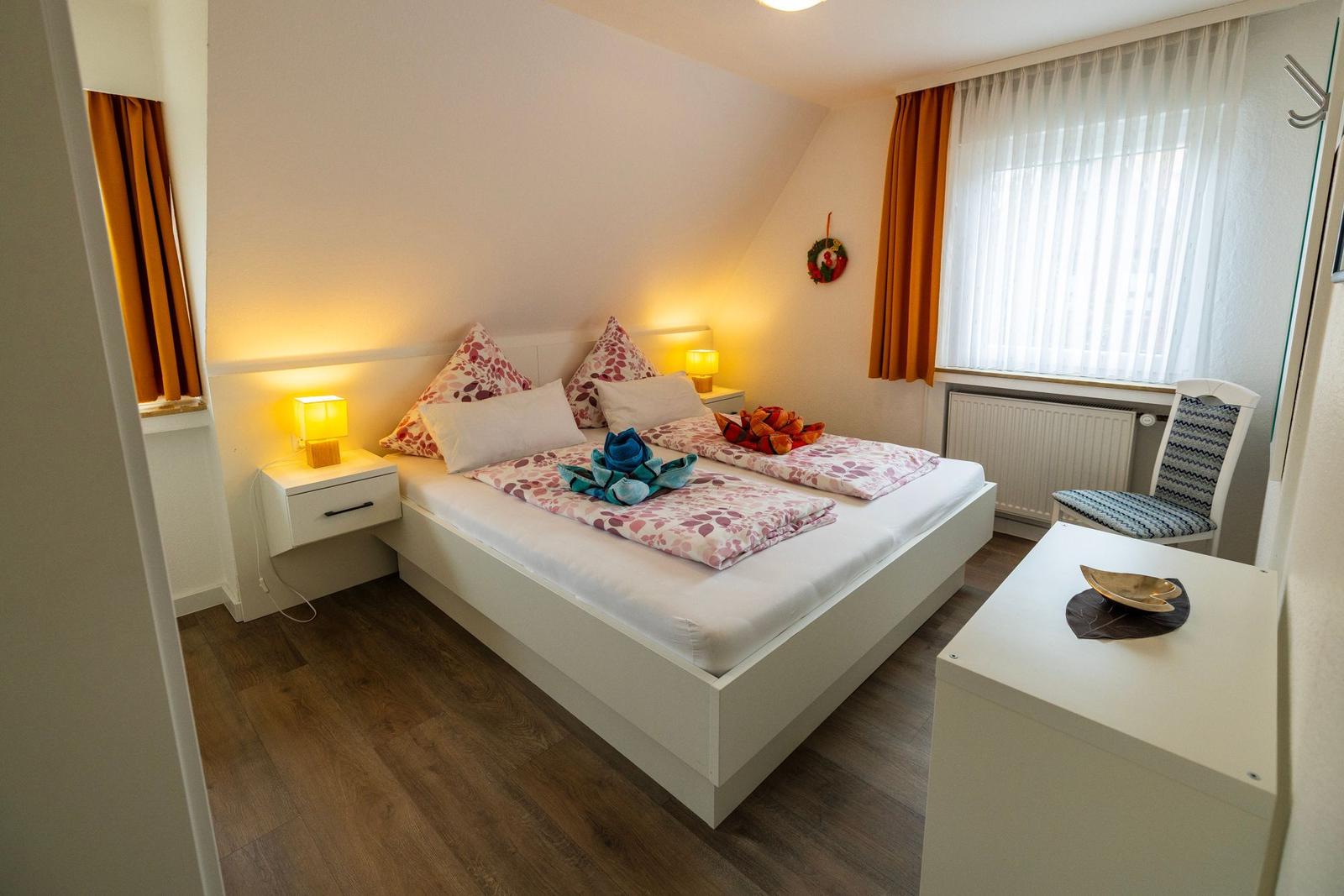 Ein Schlafzimmer mit Doppelbett, zwei Nachttischen und einem Fenster mit Vorhängen.