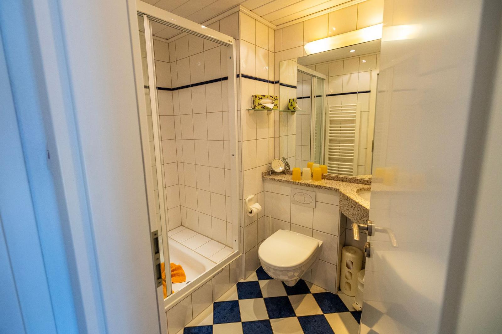 Badezimmer mit Dusche, Toilette und Waschbecken mit Spiegel.
