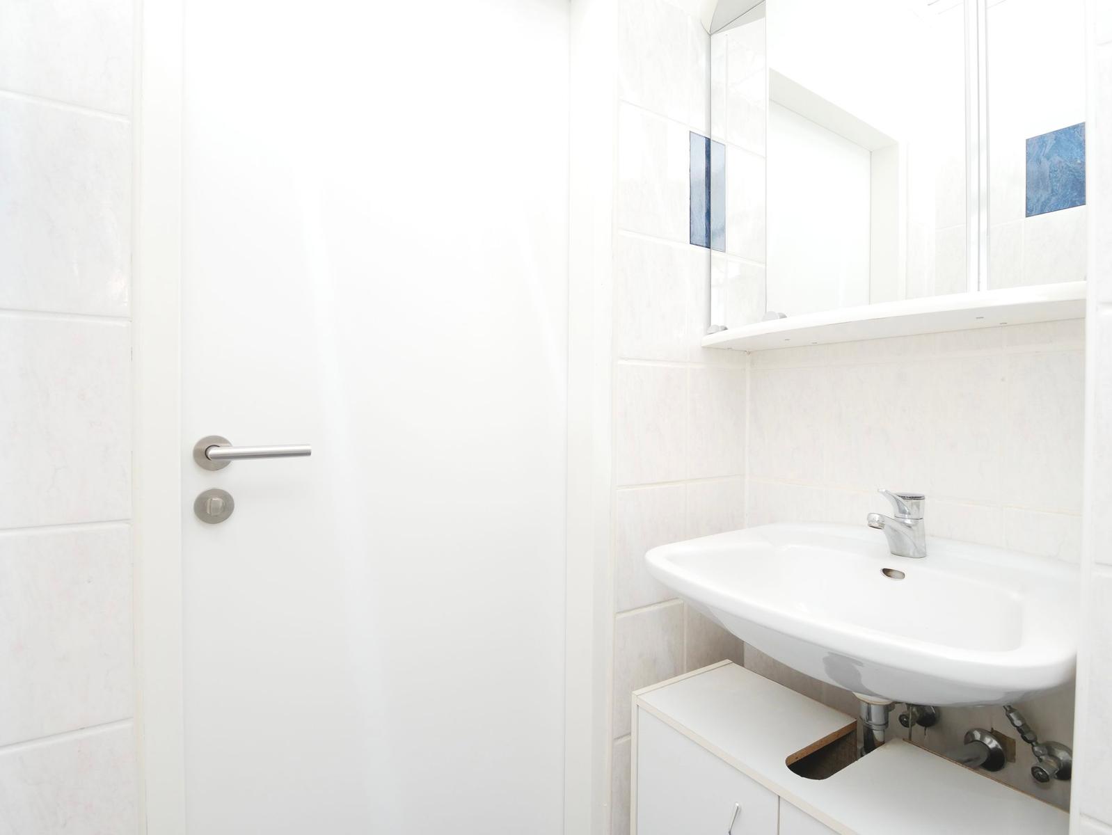 Badezimmer mit Waschbecken, Spiegel und Tür