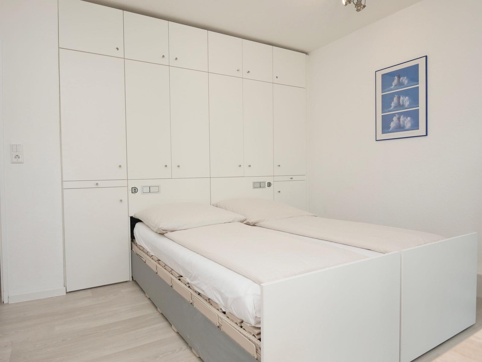 Schlafzimmer mit Doppelbett und integriertem Schrank. Wandbild mit Wolkenmotiv.