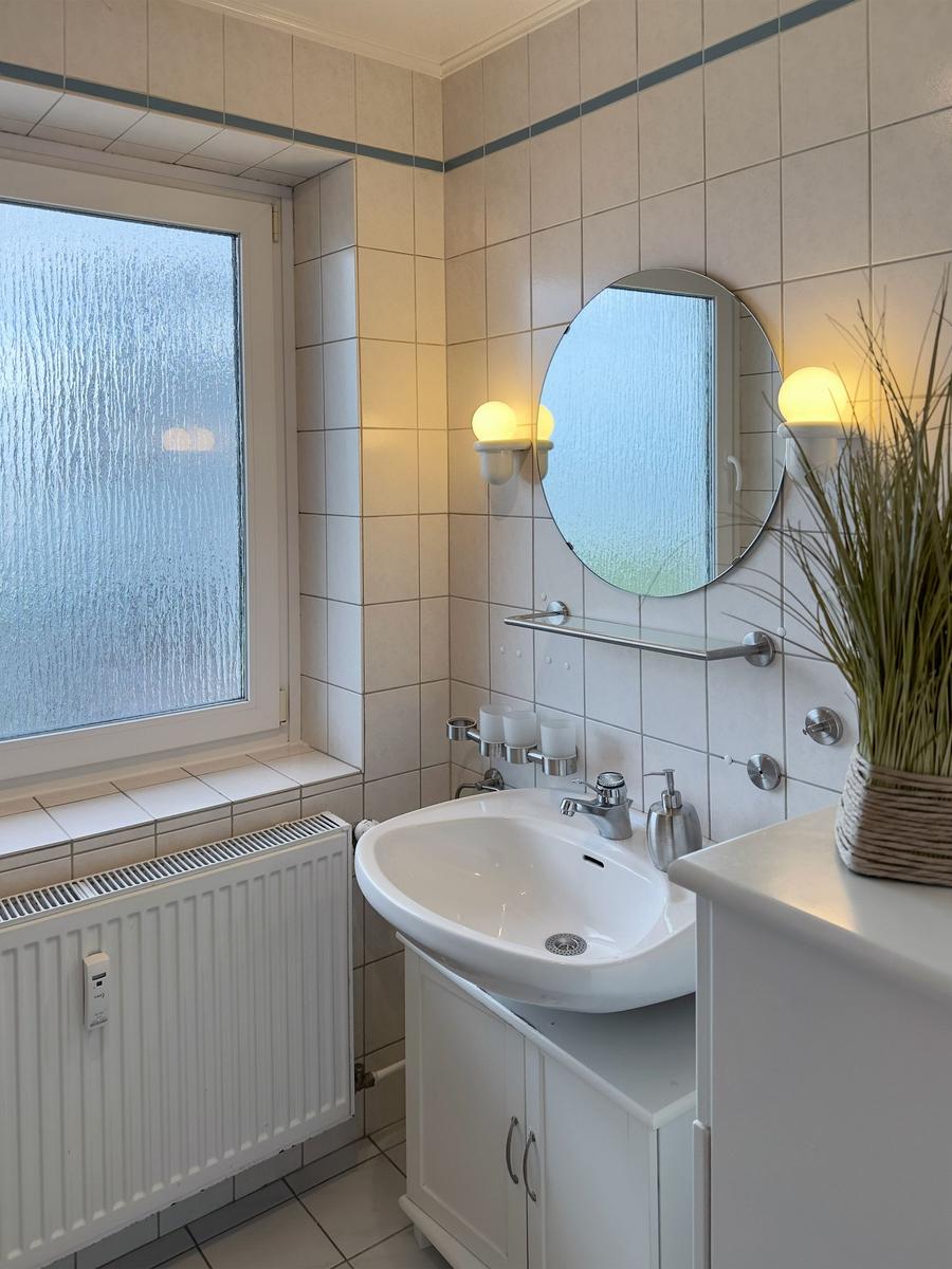 Bathroom with sink, mirror, and window with frosted glass.