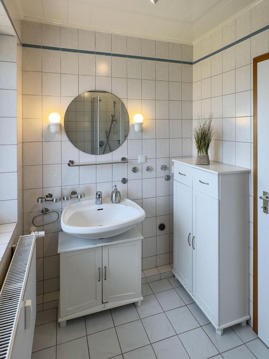 Bathroom with sink, mirror, shower, and cabinets.