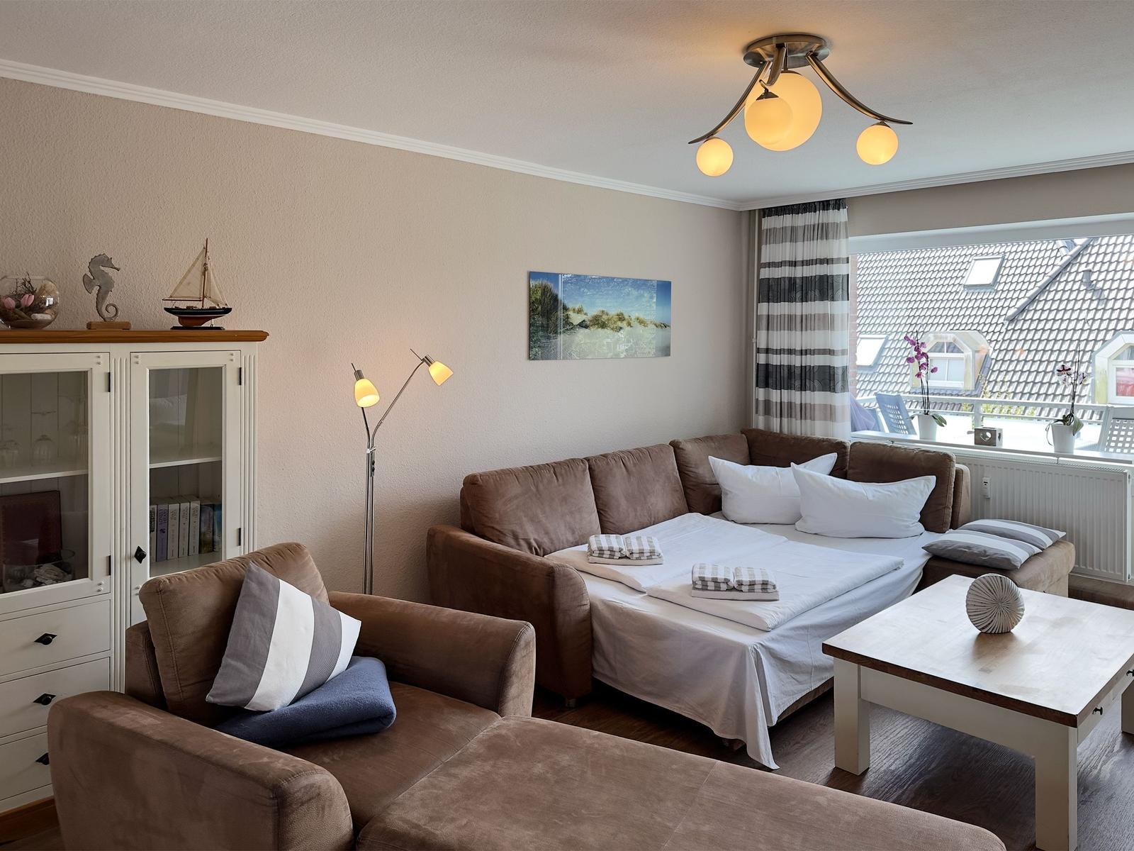 Living room with sofa bed, table, and view of rooftops