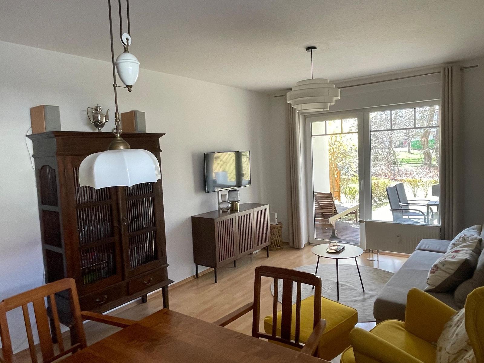 Wohn- und Essbereich mit Holzboden, Sofa, TV und Blick auf die Terrasse.