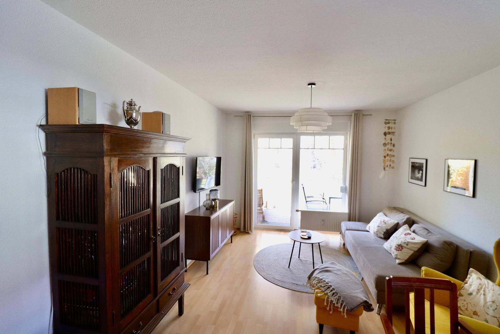 Wohnzimmer mit Sofa, Holzboden und Schwebetüren zur Terrasse.