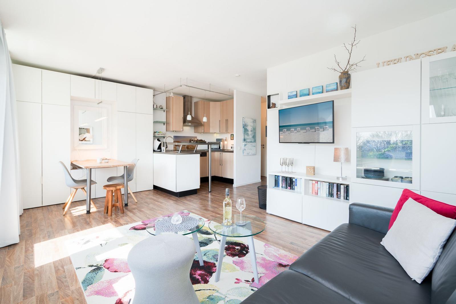 Apartment with kitchen, dining area, and living room. Sofa, TV, and glass table are visible.