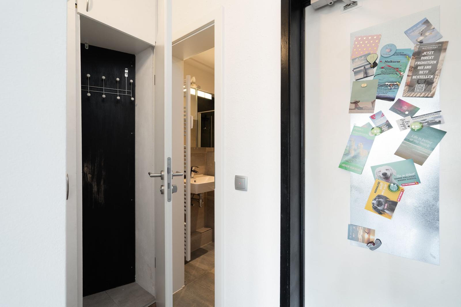 Entrance area with view into bathroom and coat hooks on the door.