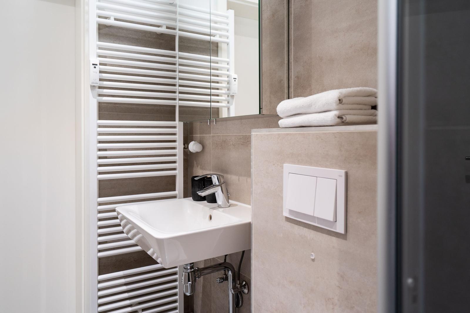 Bathroom with sink, mirror, and towel radiator.